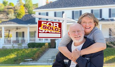 Zwei Senioren vor einem verkauften Haus