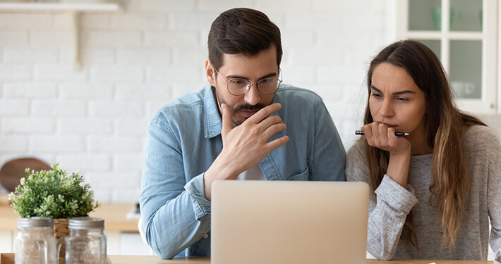 Paar informiert sich am Laptop über die Fehler beim Immobilienkauf