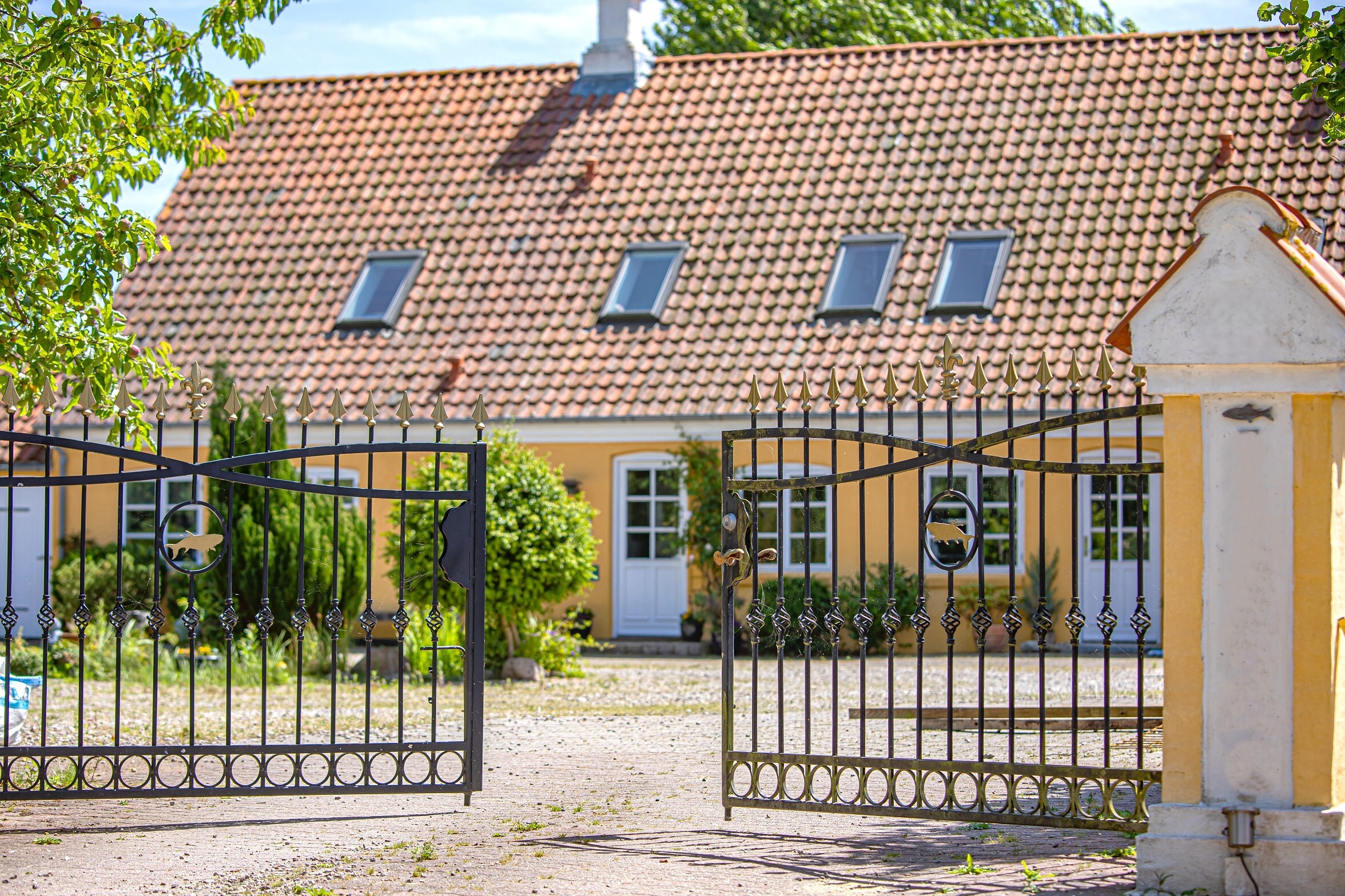 Schmiedeeisernes Einfahrtstor zu gelben Ziegelsteinhaus