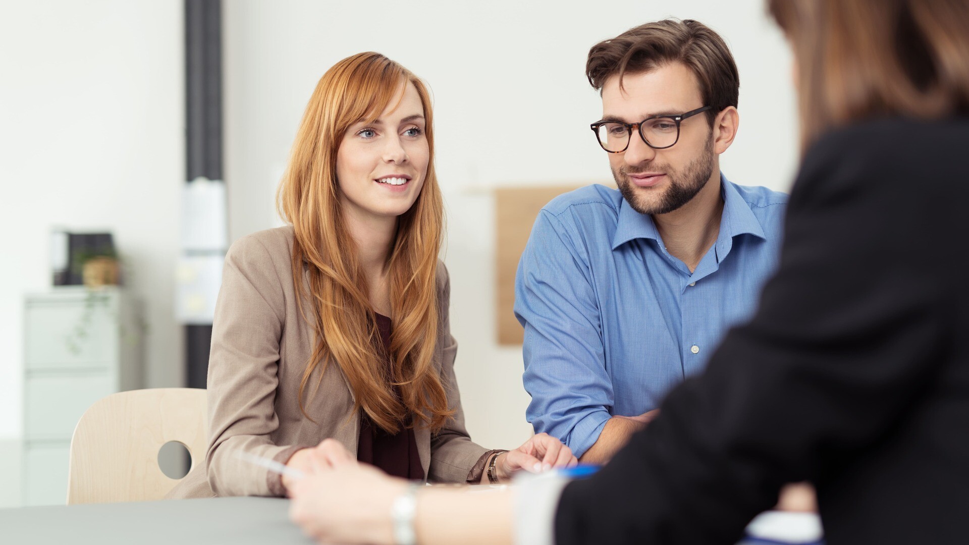 Eine Maklerin berät ein junges Paar zum Immobiliengeschäft
