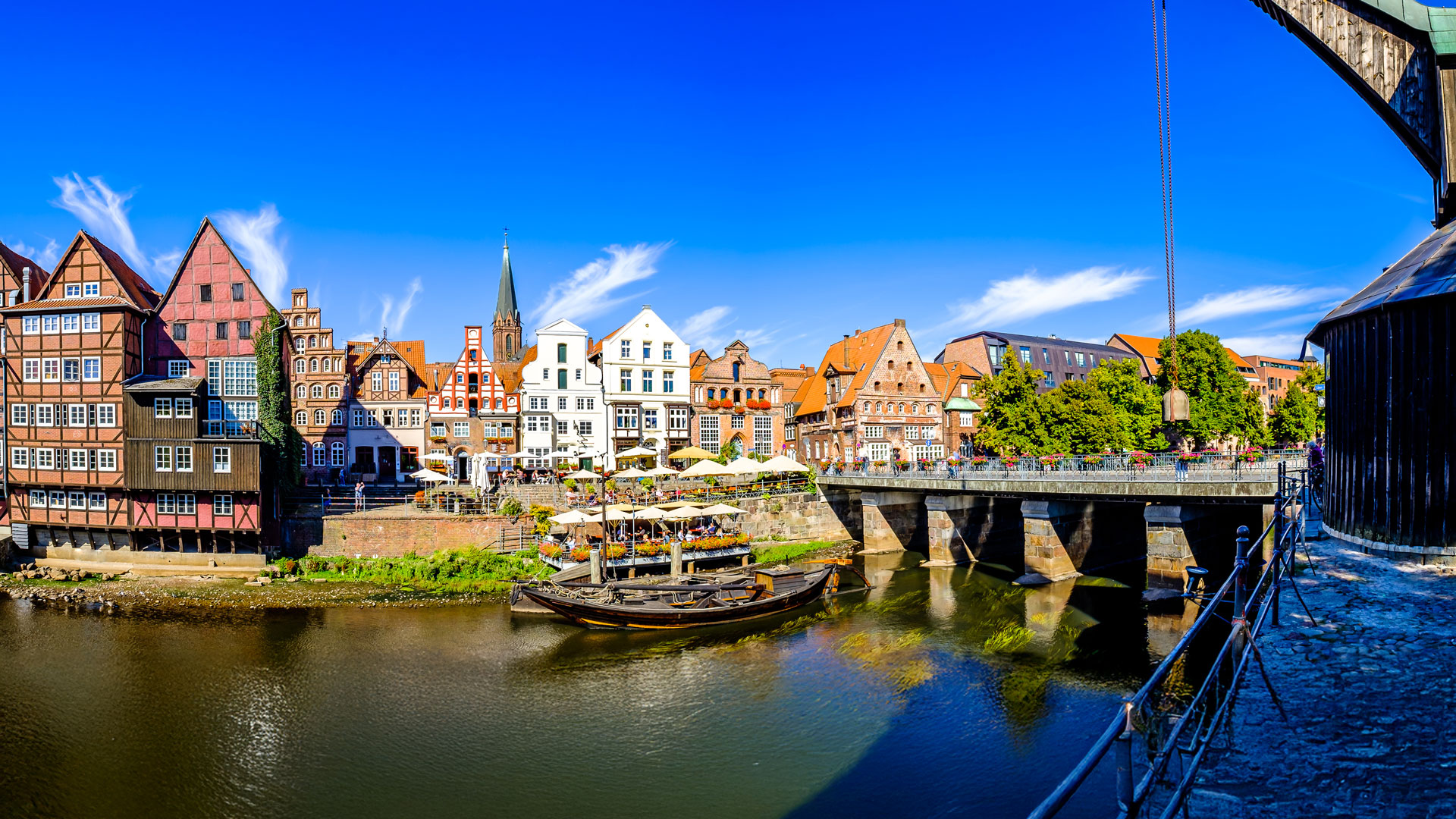 Bunte Altbauten und Café am Wasser in Lüneburg bei Sonnenschein.