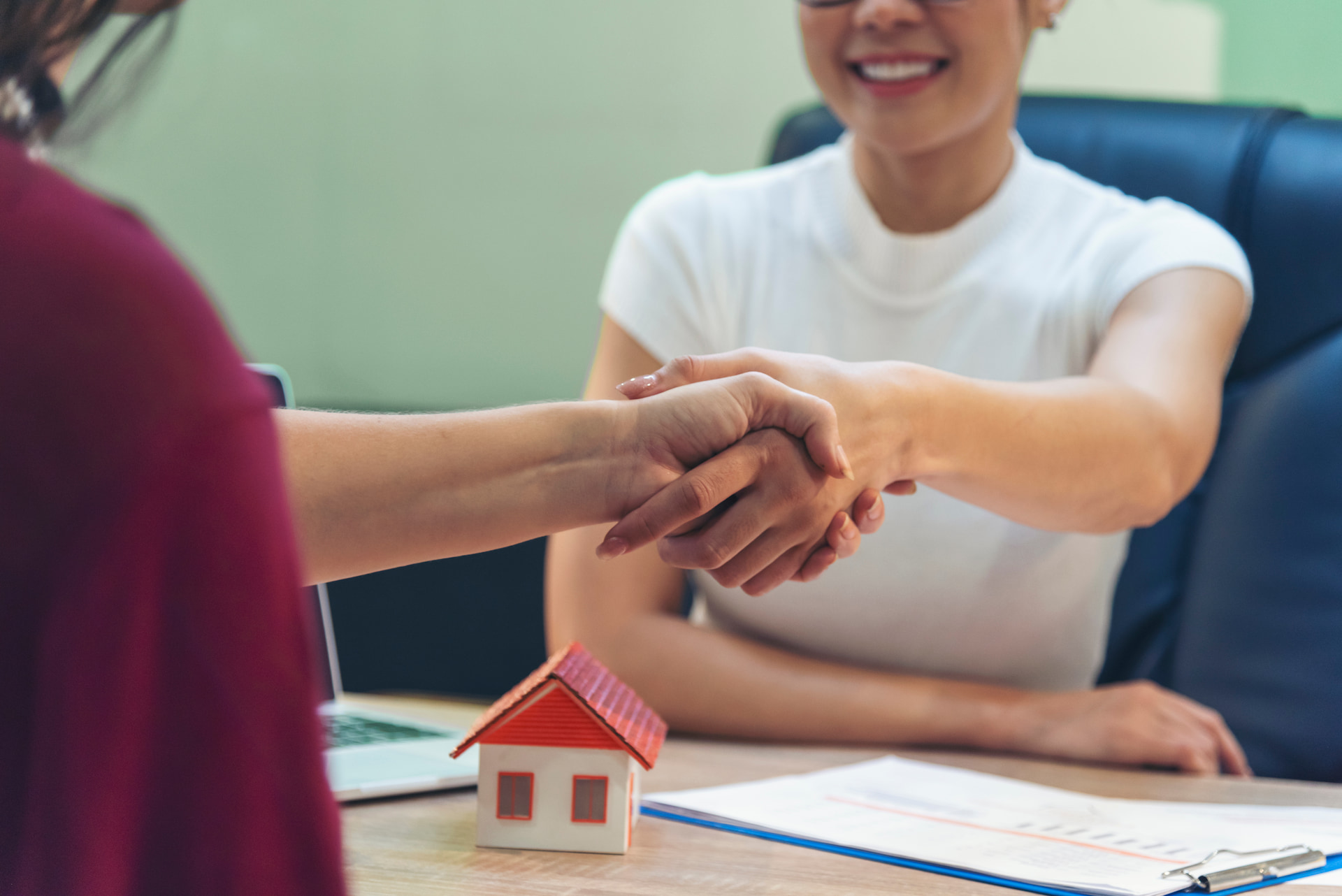 Frauen schütteln sich über Hausmodell die Hand
