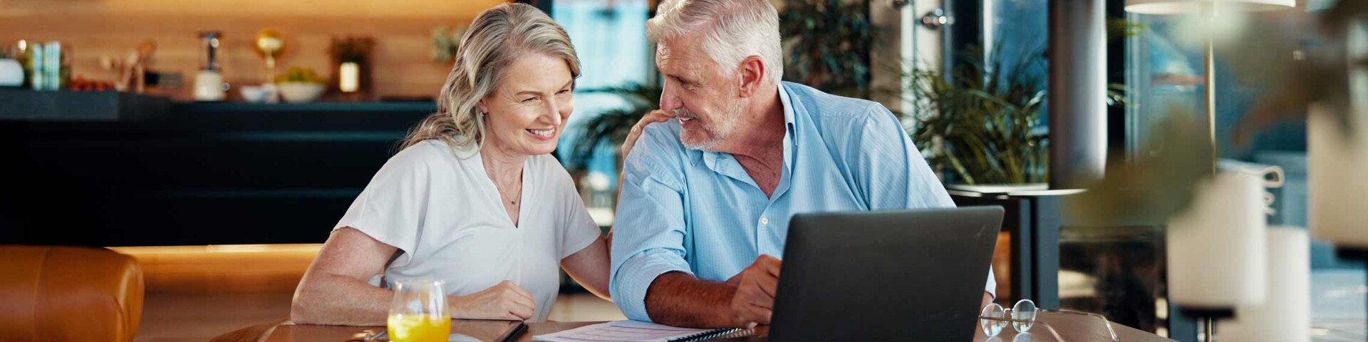 Älteres Ehepaar informiert sich zu Hause am Laptop über Immobilien als Kapitalanlagen