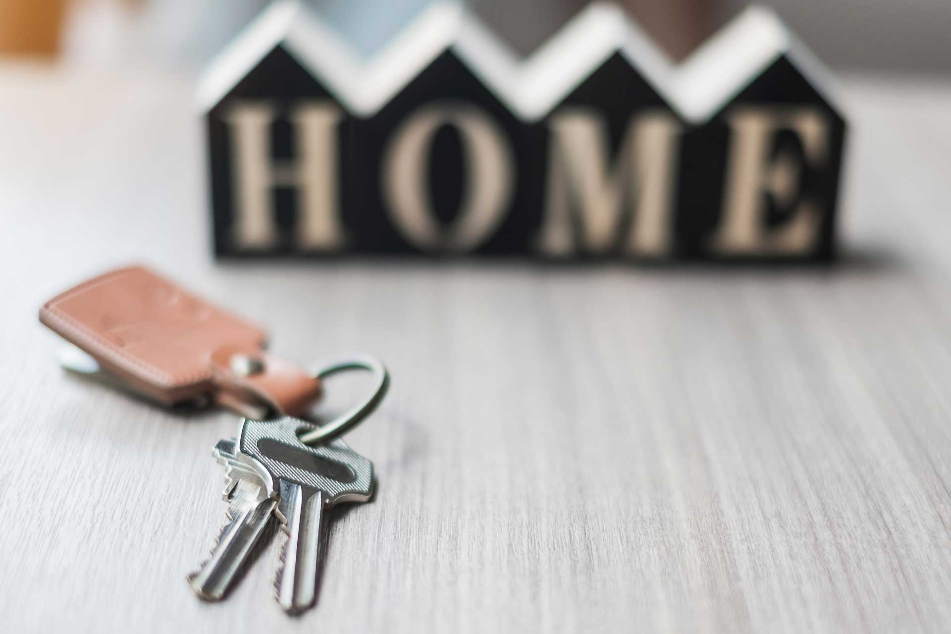 Holzwürfel mit der Aufschrift 'Home', im Vordergrund Hausschlüssel