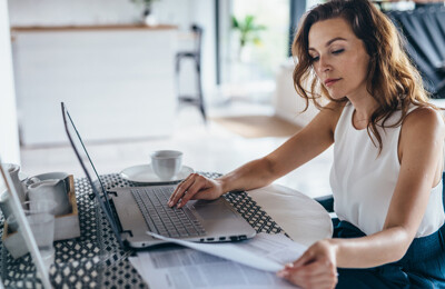 Junge Frau am Laptop mit Unterlagen