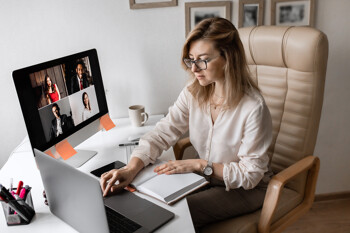 Frau sitzt am Schreibtisch mit Monitoren im Home-Office