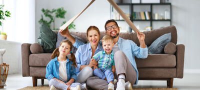 Familie sitzt vor Sofa