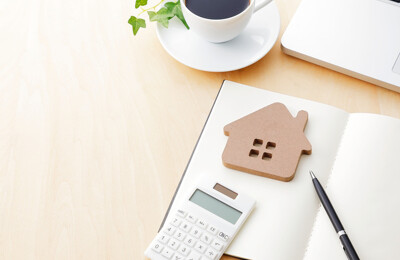 Modellhaus mit Notizbuch, Stift und Taschenrechner
