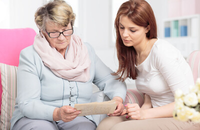 Seniorin sitzt mit Enkelin auf dem Sofa