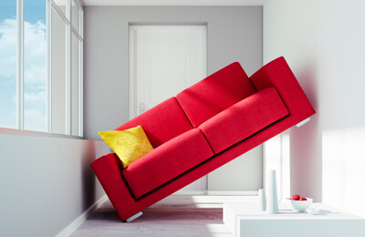 Rotes Sofa steht schräg zwischen zwei Wänden