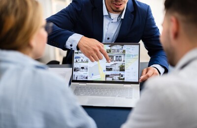 Ein Makler zeigt Immobilien auf einem PC