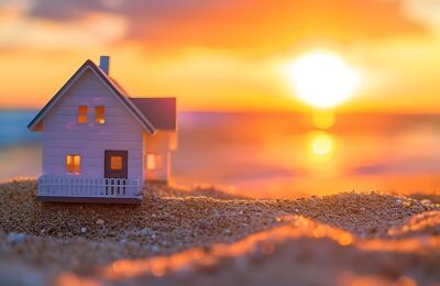 Kleines Modellhaus am Strand vor Sonnenuntergang