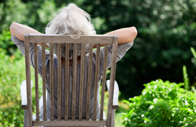 Seniorin lehnt sich im Gartenstuhl zurück