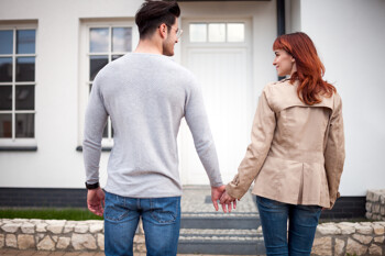 Paar steht Hand in Hand vor der Haustür