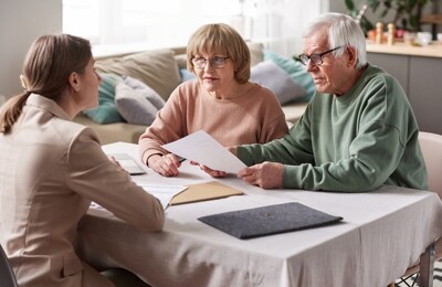 Ein älteres Ehepaar wird von einer Maklerin beraten