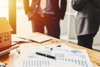 Makler und Kunde stehen an einem Tisch