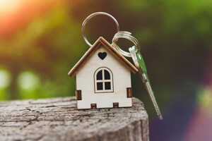 Hausschlüssel mit kleinem Haus als Anhänger symbolisiert den Hauskauf