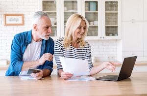 Älteres Ehepaar sichtet die Unterlagen zum Immobilienverkauf