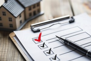 Checkliste mit Häkchen und Modellhaus