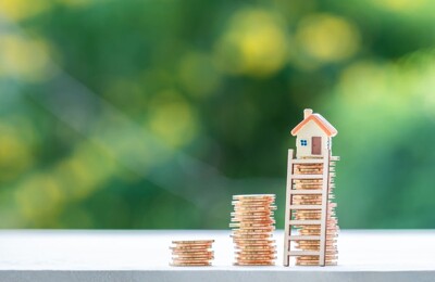 Ein Hausmodell steht auf einem Münzstapel