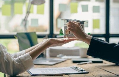 Ein Immobilienmakler übergibt einen Schlüssel an eine Kundin