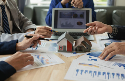 Immobilienmakler und Kunden sitzen an einem Tisch