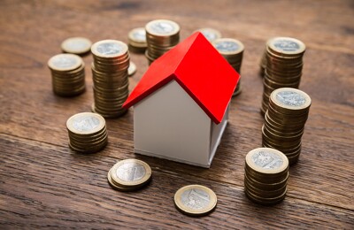 Münzen liegen um Modellhaus