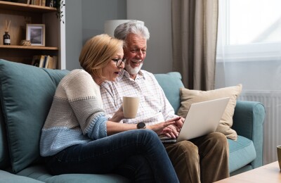 Senioren sitzen gemeinsam vor Laptop