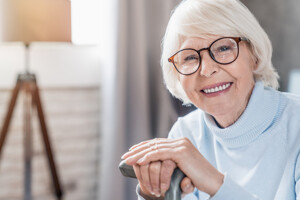 Fröhliche ältere Dame lehnt sich auf ihren Stock