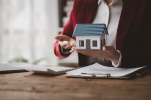 Makler hält ein Hausmodell
