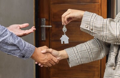Maklerin überreicht Mieter die Schlüssel