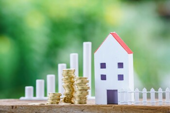 Modellhaus mit kleinen Münzstapeln daneben