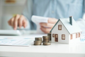 Immobilienbewertung Geldstücke neben Hausmodell