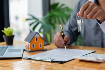 Hausmodell mit Unterlagen auf Schreibtisch