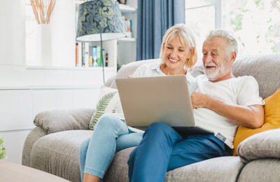 Zufriedenes Ehepaar mit Laptop auf Sofa