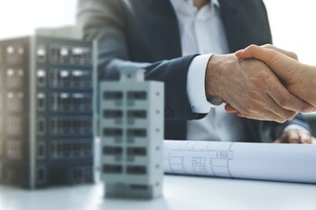 Handschlag neben Hausmodell