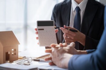 Person zeigt zweiter Person die Summe auf dem Taschenrechner