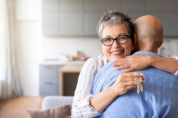 Umarmende Senioren zeigen Schlüssel