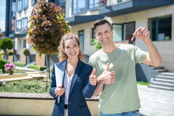 Mann mit Maklern hält Schlüssel in der Hand