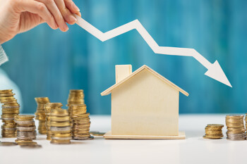 Modellhaus neben sinkendem Pfeil