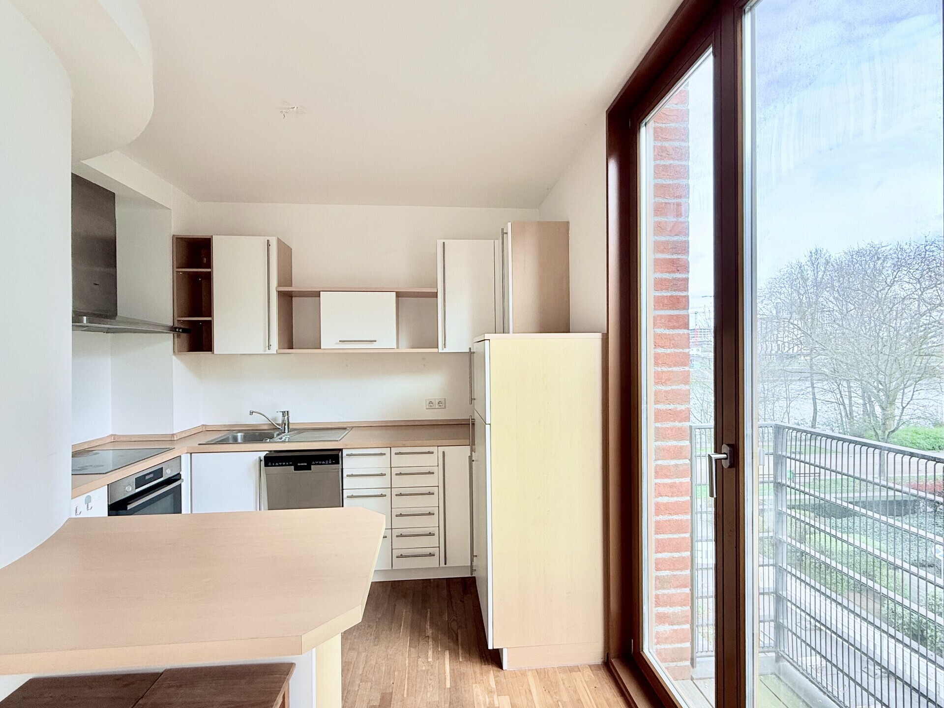 Helle Wohnküche mit kleinem Balkon und Wasserblick