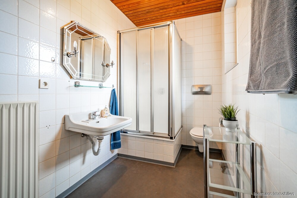 Das Duschbad mit Tageslicht ist weiß gefliest.