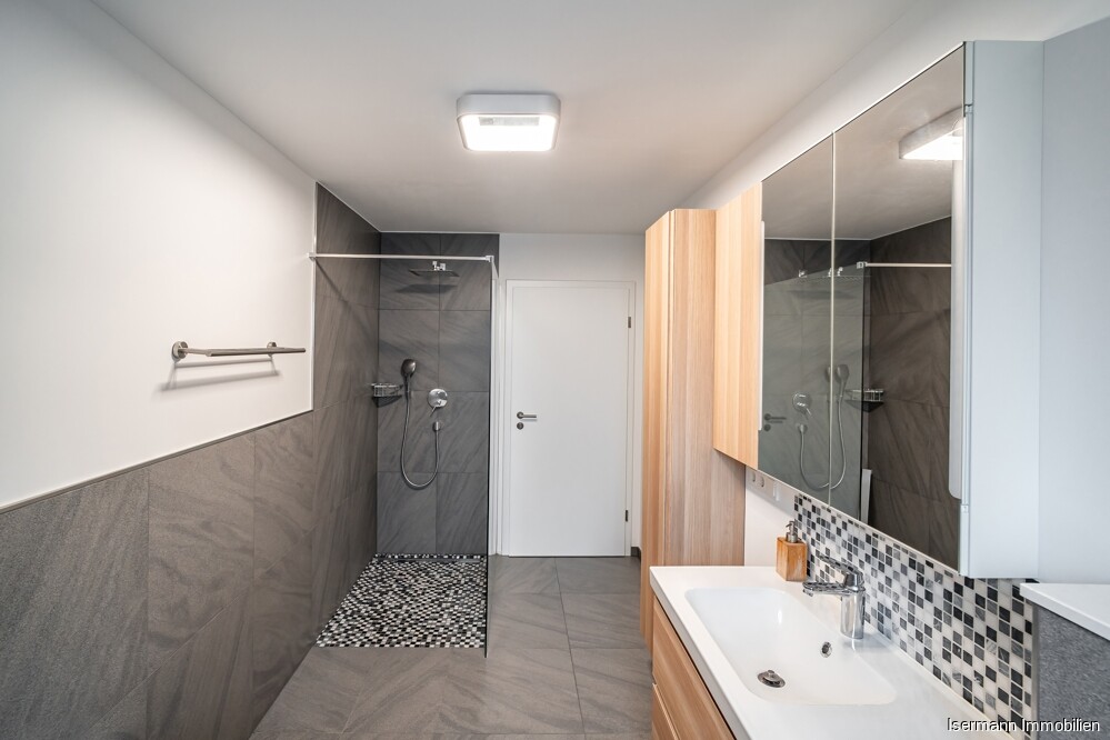 Der Raum ist mit einer Wanne und einer bodengleichen Glasdusche ausgestattet.