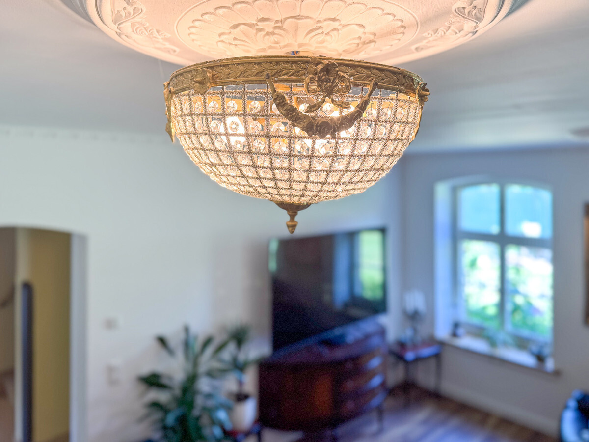 Detailaufnahme der verzierten Deckenrosette im Wohnzimmer