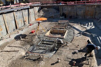 Arbeiter stellen Bewehrungsstäbe und Holzschalungen auf einer Baustelle auf.