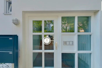 Weiße Glastüren mit Klingel, blaue Briefkästen und Wandlampe.