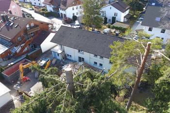 Gefallener Baum liegt auf Hausdach neben weiteren Häusern.