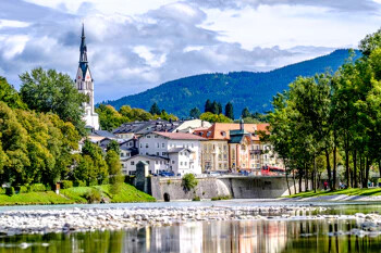 Kleinstadt mit Kirche, bunten Häusern, Fluss und Bergen.
