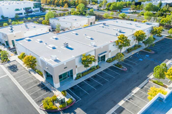 Modernes Bürogebäude mit leeren Parkplätzen und grünen Bäumen.