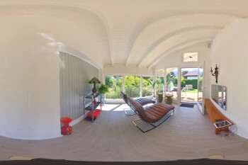 Modernes Wohnzimmer mit großen Fenstern, Sesseln, Gartenblick.